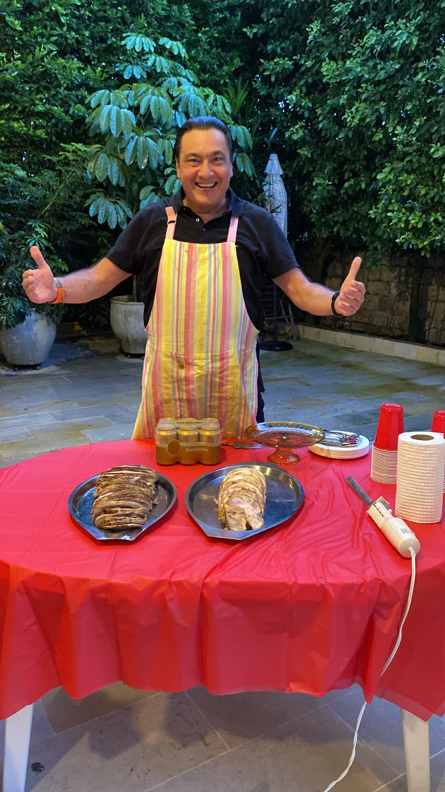 El Chino sonriendo con el pernil y el pollo relleno listos en la mesa
