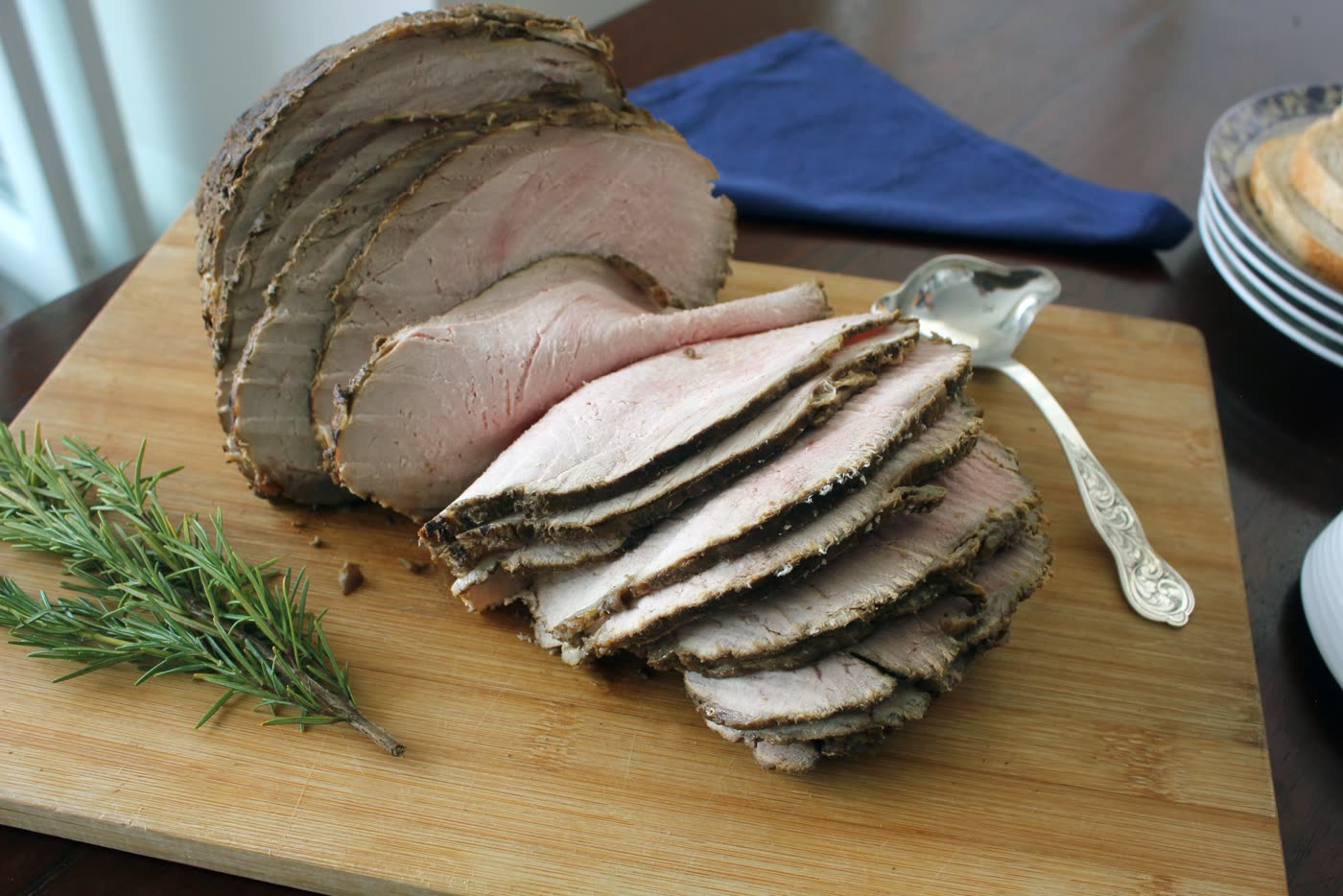 Pernil de cerdo en rodajas con romero sobre una tabla